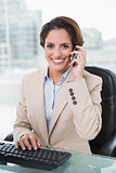 Cheerful businesswoman phoning and looking at camera