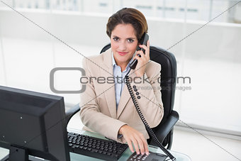 Brunette businesswoman using phone and smiling at camera