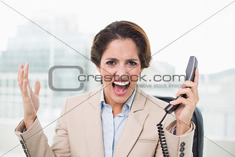 Furious businesswoman looking at camera and holding phone