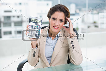 Worried businesswoman holding calculator