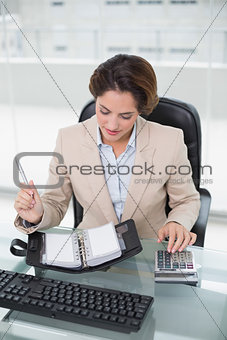Businesswoman using calculator and looking at diary