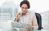 Businesswoman reading newspaper at her desk