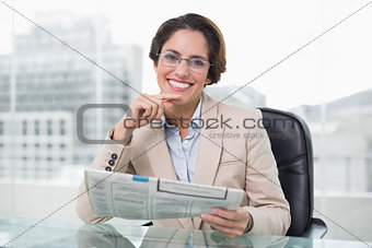Businesswoman holding newspaper at her desk