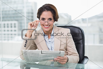 Smiling businesswoman holding newspaper at her desk