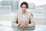 Serious businesswoman looking at camera at her desk