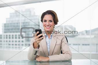 Businesswoman smiling and holding her smartphone
