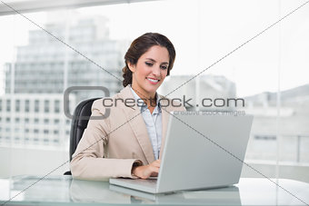 Happy businesswoman typing on laptop at her desk