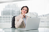 Thoughtful businesswoman using laptop at her desk