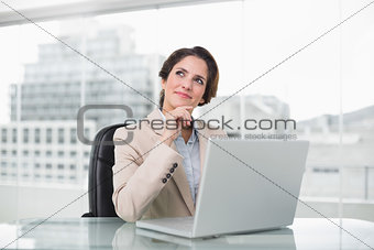 Thoughtful businesswoman using laptop at her desk