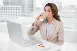 Businesswoman drinking coffee at her desk in front of laptop