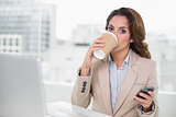 Attractive businesswoman drinking from disposable cup