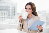 Beautiful content businesswoman using tablet drinking coffee