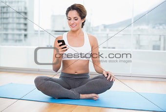 Sporty smiling brunette looking at smartphone