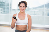 Sporty smiling brunette holding smartphone