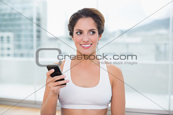Sporty happy brunette holding smartphone