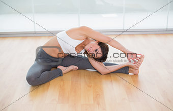 Sporty happy brunette stretching on the floor