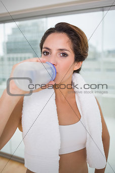 Sporty calm brunette drinking from water bottle