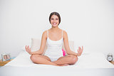 Happy young brown haired model in white pajamas practicing yoga