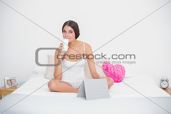 Relaxed young brown haired model in white pajamas drinking milk