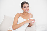 Dreamy young brown haired model in white pajamas drinking coffee