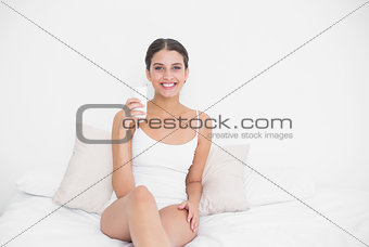 Peaceful young brown haired model in white pajamas drinking milk