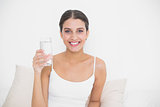 Attractive young brown haired model in white pajamas holding a glass of water