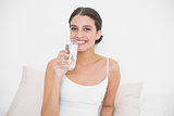 Charming young brown haired model in white pajamas drinking water