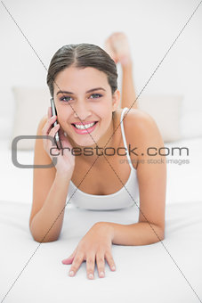 Casual young brown haired model in white pajamas making a phone call