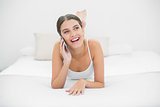 Casual young brown haired model in white pajamas calling with her mobile phone