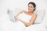 Casual young brown haired model in white pajamas holding a tablet pc