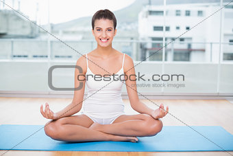 Smiling natural brown haired woman in white sportswear practicing yoga