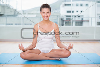 Happy natural brown haired woman in white sportswear practicing yoga