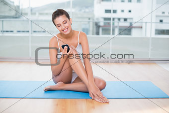 Content natural brown haired woman in white sportswear using her mobile phone