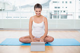 Pleased natural brown haired woman in white sportswear using a tablet pc