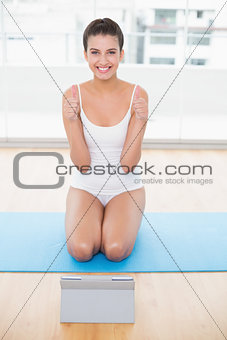Charming natural brown haired woman in white sportswear giving thumbs up