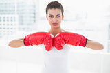 Serious natural brown haired woman in white sportswear wearing boxing gloves