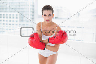 Dynamic natural brown haired woman in white sportswear wearing boxing gloves