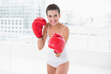 Content natural brown haired woman in white sportswear wearing boxing gloves
