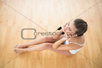 Peaceful natural brown haired woman in white sportswear listening to music