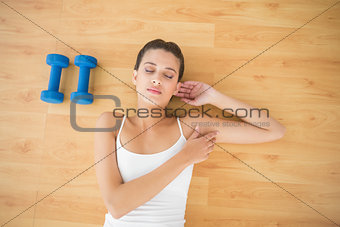 Peaceful natural brown haired woman in white sportswear sleeping on the floor