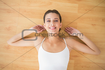 Relaxed natural brown haired woman in white sportswear lying on the floor