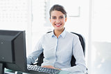Happy classy brown haired businesswoman using a computer