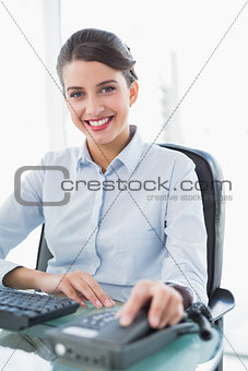 Smiling classy brown haired businesswoman hanging up the telephone