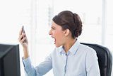 Angry classy brown haired businesswoman shouting at her mobile phone