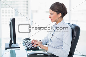 Concentrated classy brown haired businesswoman typing on a computer