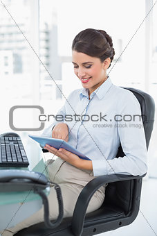 Smiling classy brown haired businesswoman using a tablet pc