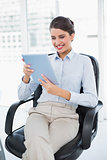 Delighted classy brown haired businesswoman using a tablet pc