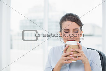 Peaceful classy brown haired businesswoman enjoying coffee smell