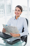 Content classy brown haired businesswoman reading a newspaper