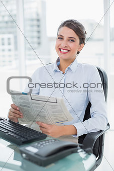 Content classy brown haired businesswoman reading a newspaper